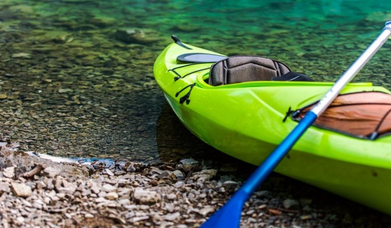 green kayak parked on the shore - ee220329