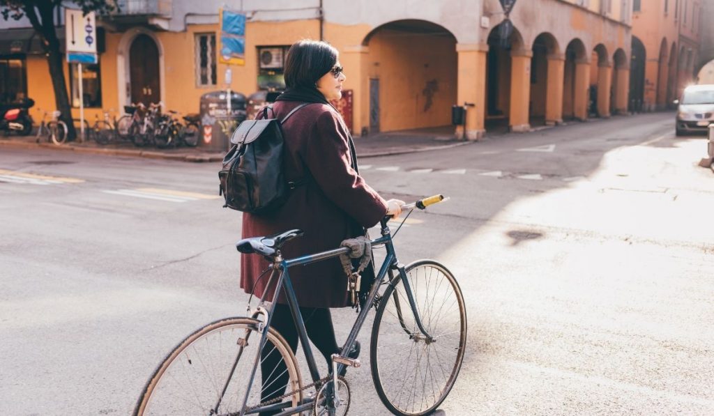 plus size woman walking in the street while holding her bicycle - ee220329