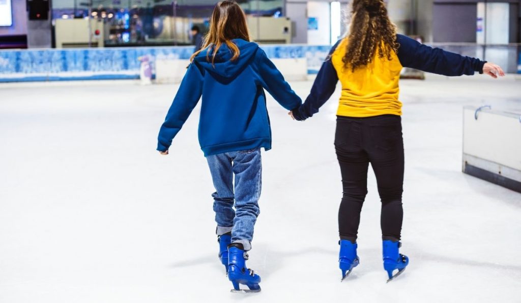 two ladies holding hands while skating - ee220321