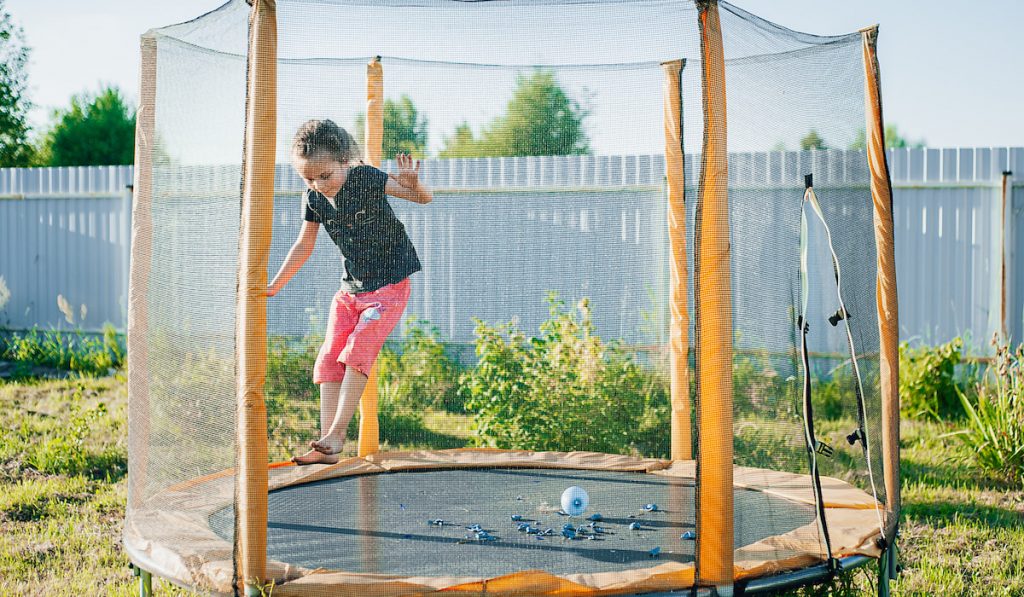 cute girl jumping on a trampoline in the backyard