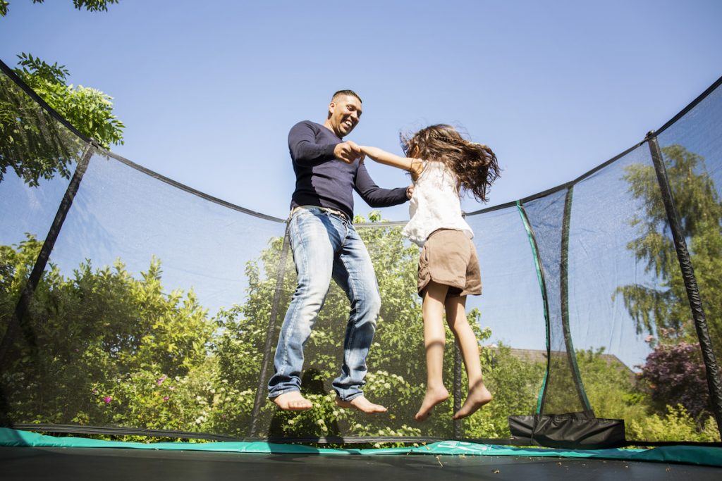 father and daughter jumping on trampoline