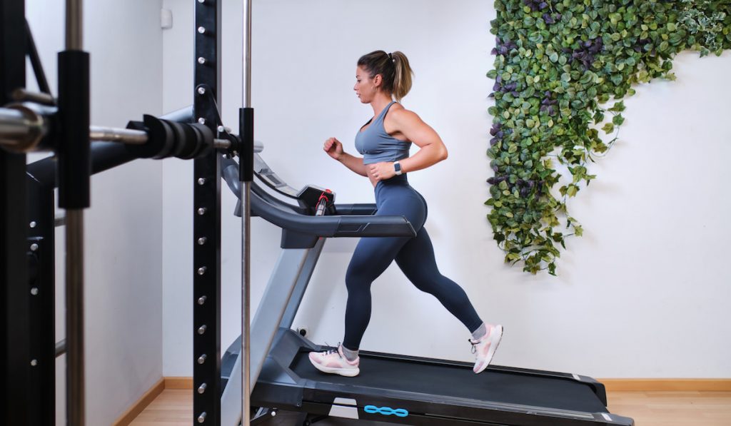 fit woman running on incline treadmill in a gym 