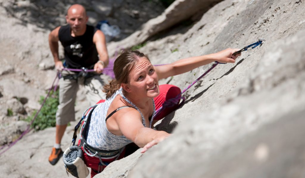 lady rock climber climbing rock with her partner