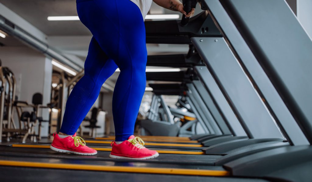 low section of overweight woman exervising on treadmill 