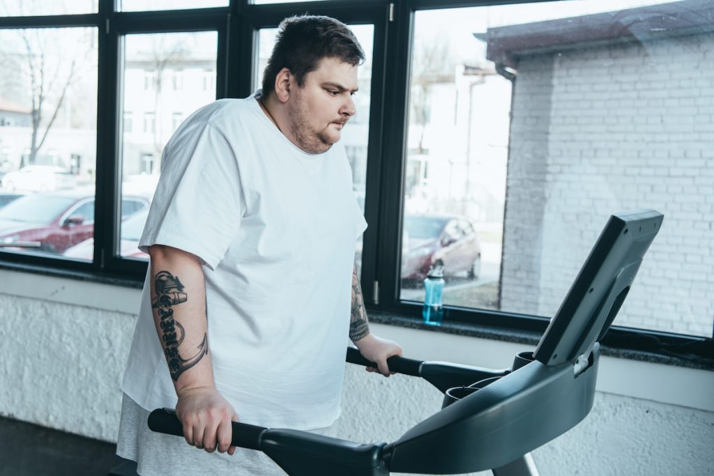 overweight tattoed man running on treadmill