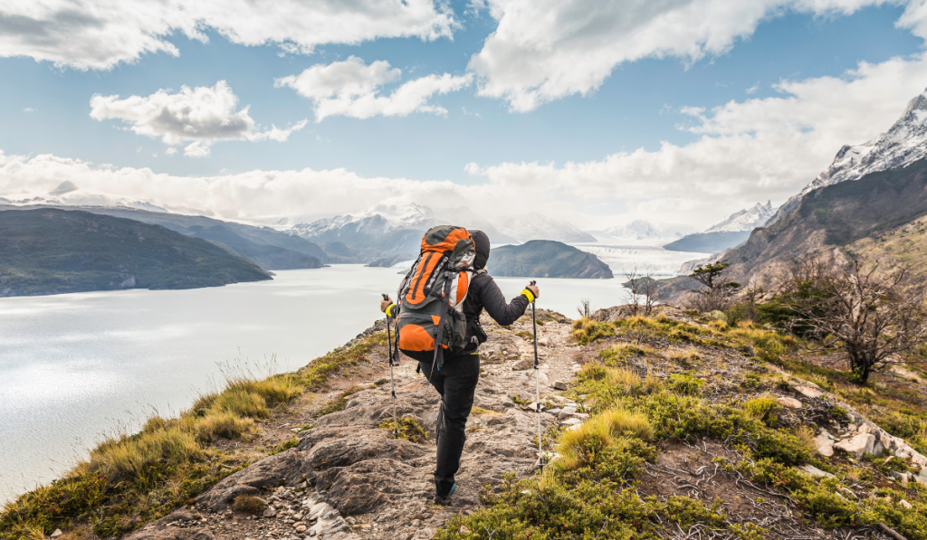 female hiker hiking alongside Grey glacier lake