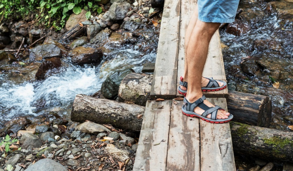 man wearing sandals standing in a wooden plank in the woods